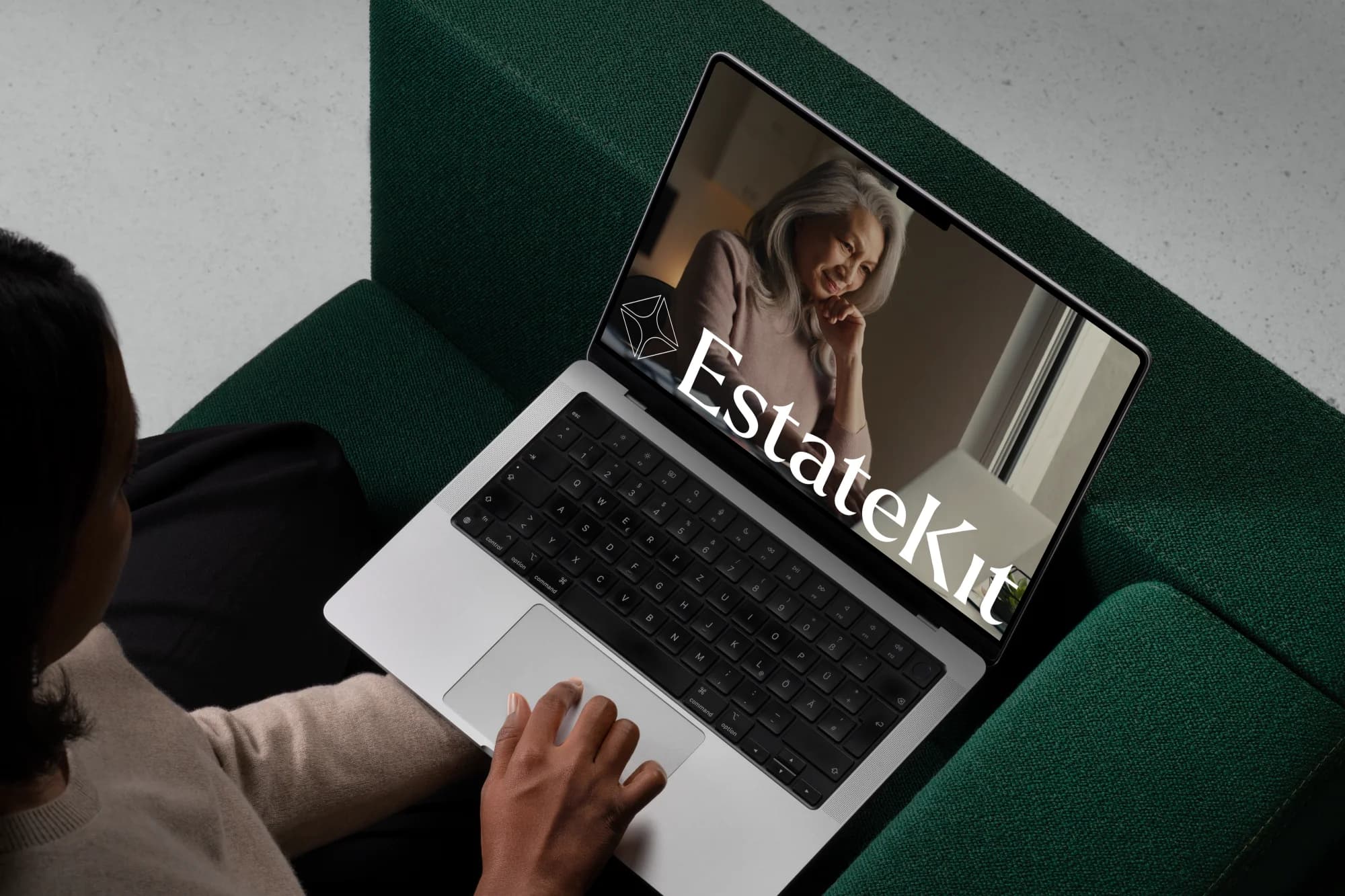 Estate Kit's site on a laptop, its wordmark over a photograph of an older woman, on the lap of someone sitting on a green sofa.