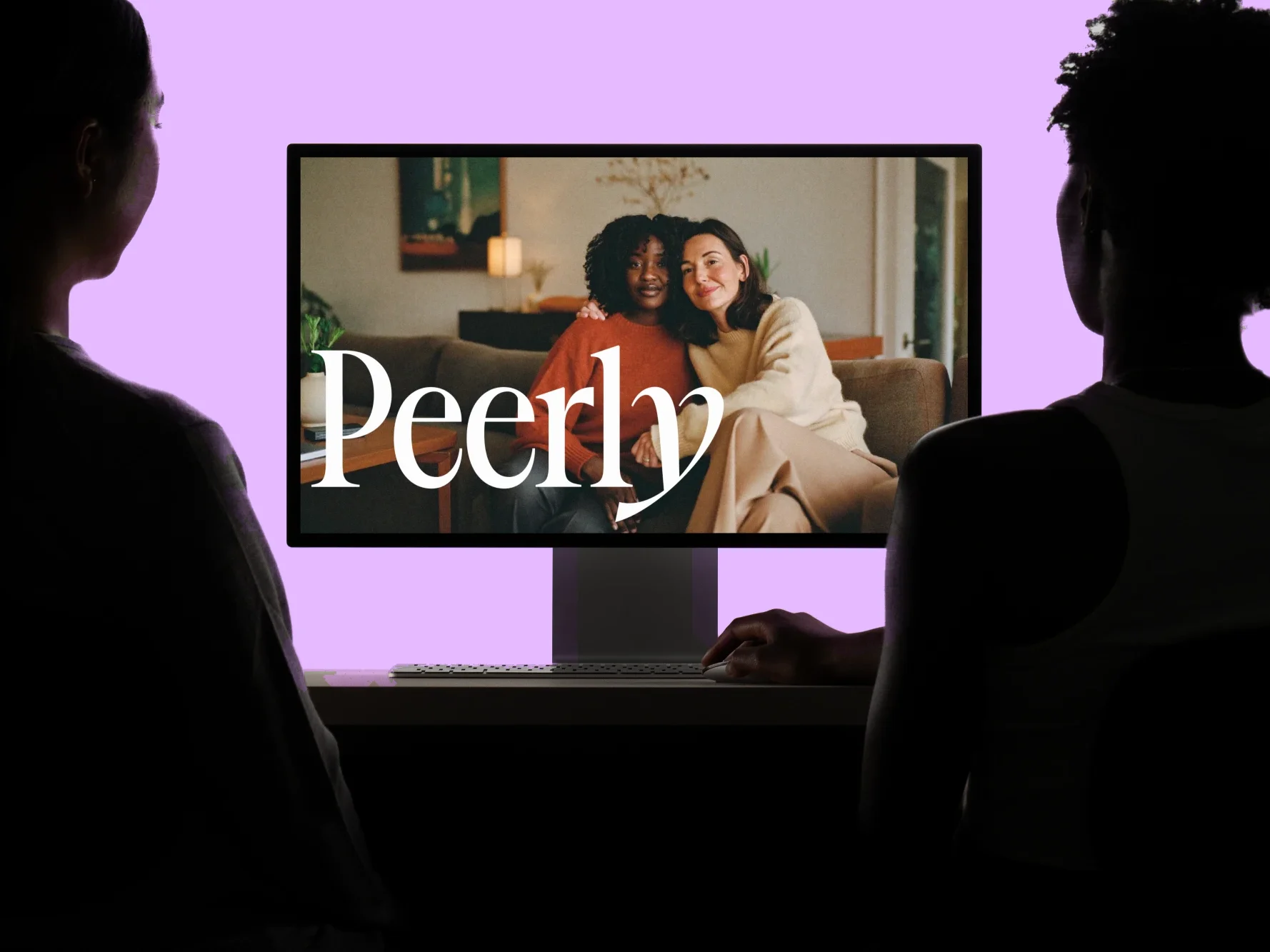 Peerly's wordmark over a photograph of two women on a sofa, on a desktop monitor two people are sitting at.