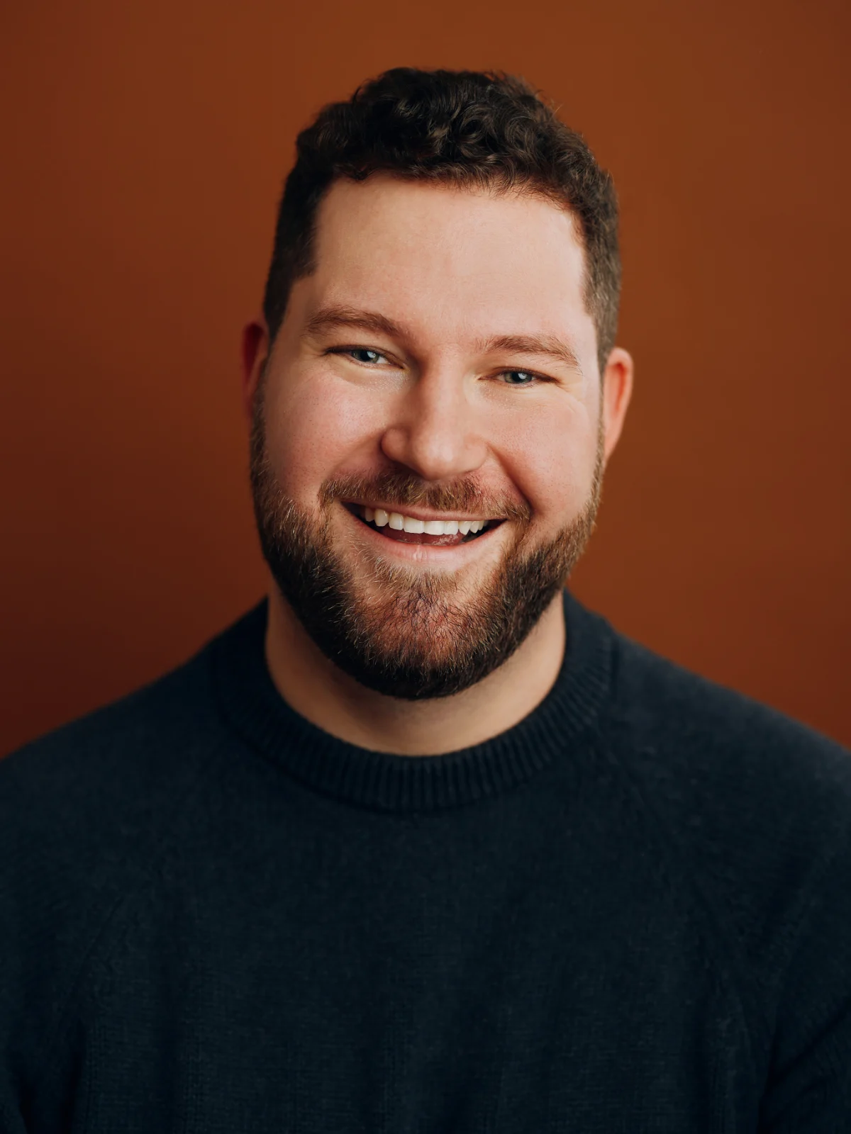 Martin Laws, smiling, photographed against a rust-coloured wall.